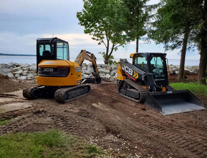 Two large pieces of heavy equipment digging to restore a shoreline